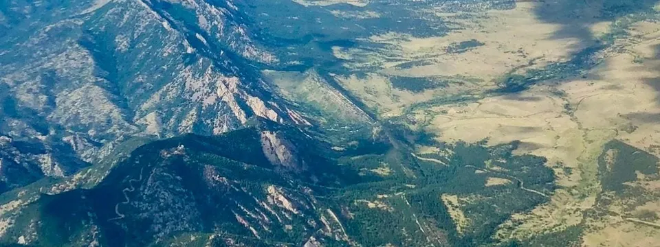 The Colorado Front Range from the air: tilted sandstone slabs and forested foothills dropping away to the towns on the plains